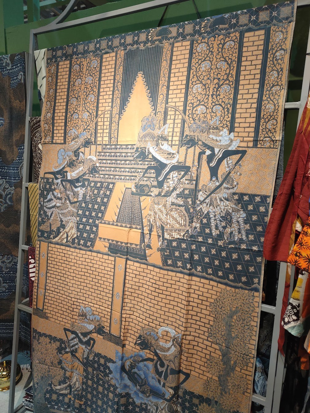 Large Indonesian textile depicting wayang figures and architectural motifs displayed at KKI